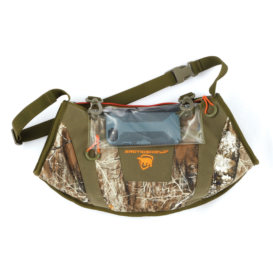 Front view of RealTree Apex hand warmer with orange accent zippers, an orange logo, and a clear pocket.