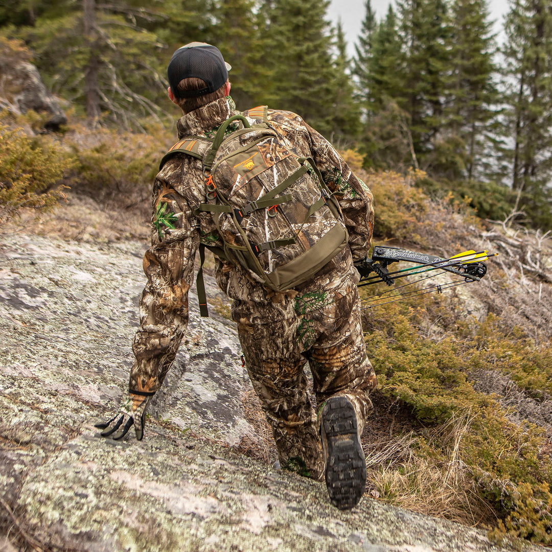 Hunter in Heat Echo Stalker Pant with a backpack and crossbow climbing rocky terrain.