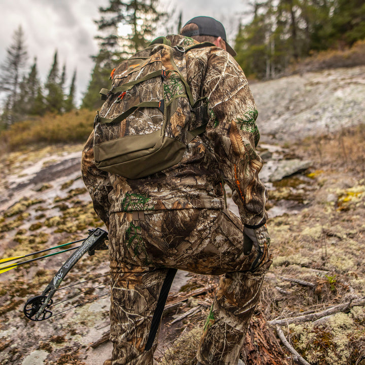 Hunter in Heat Echo Stalker Jacket with a backpack, bow, and arrows in a forest setting.