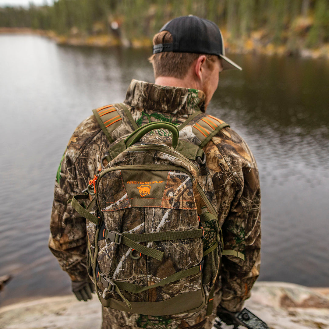 Person in Heat Echo Stalker Jacket and backpack standing by a body of water.