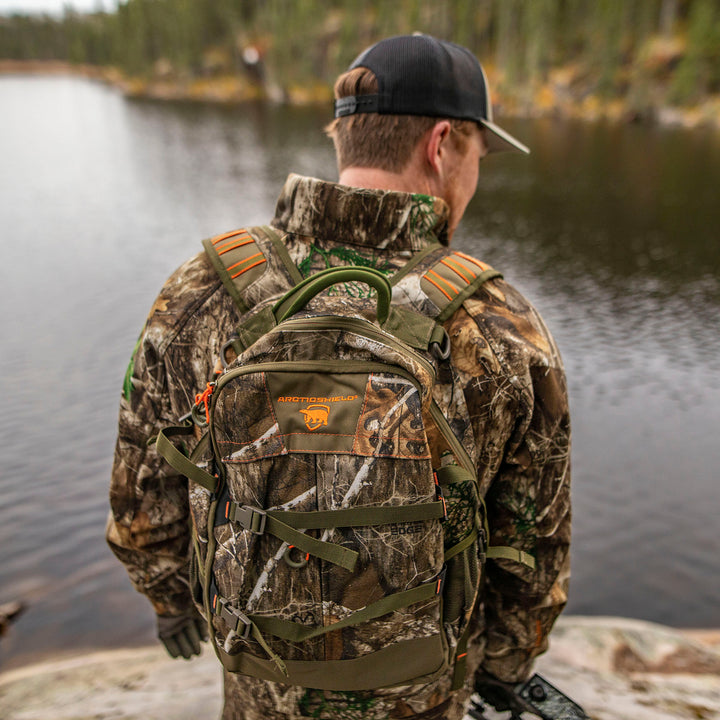 Person in Heat Echo Stalker Jacket and backpack standing by a body of water.