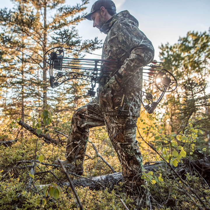 Hunter in Heat Echo Raider Pant with a bow in a forest setting.