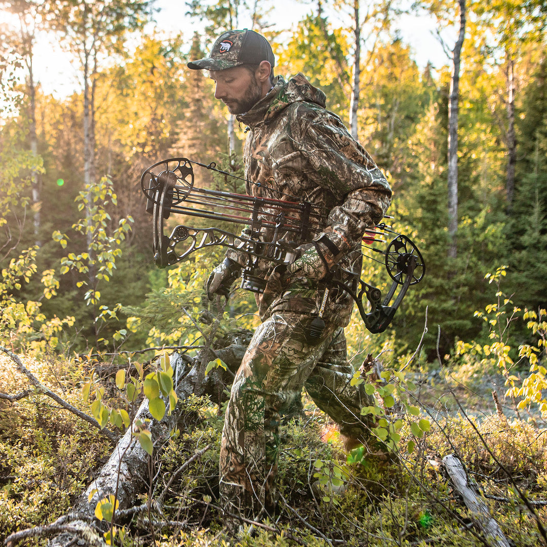 Man in Heat Echo Raider Pant holding a bow in a forest setting.